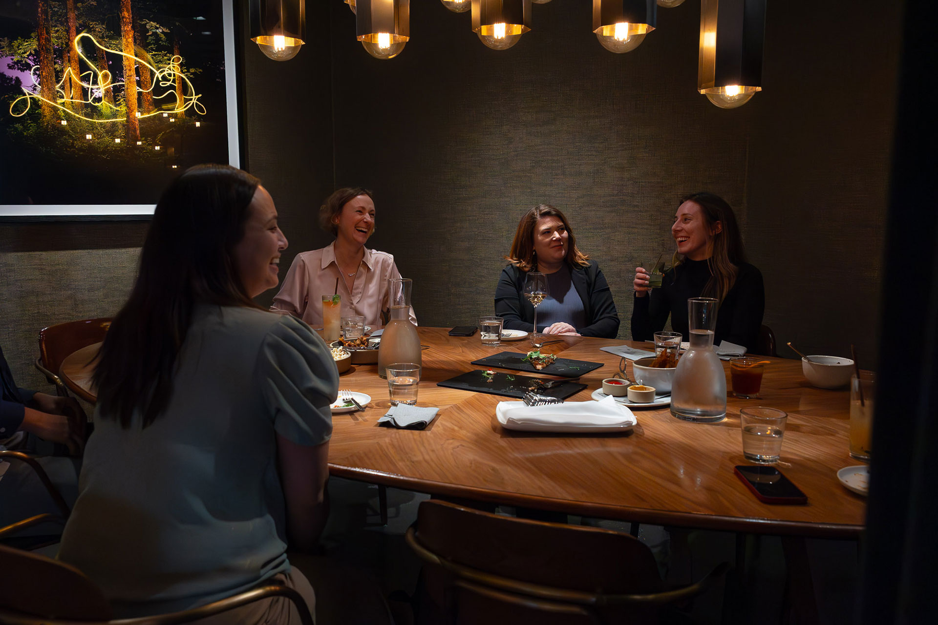 Four women laughing over a meeting in the dining room at The Ameswell Hotel.